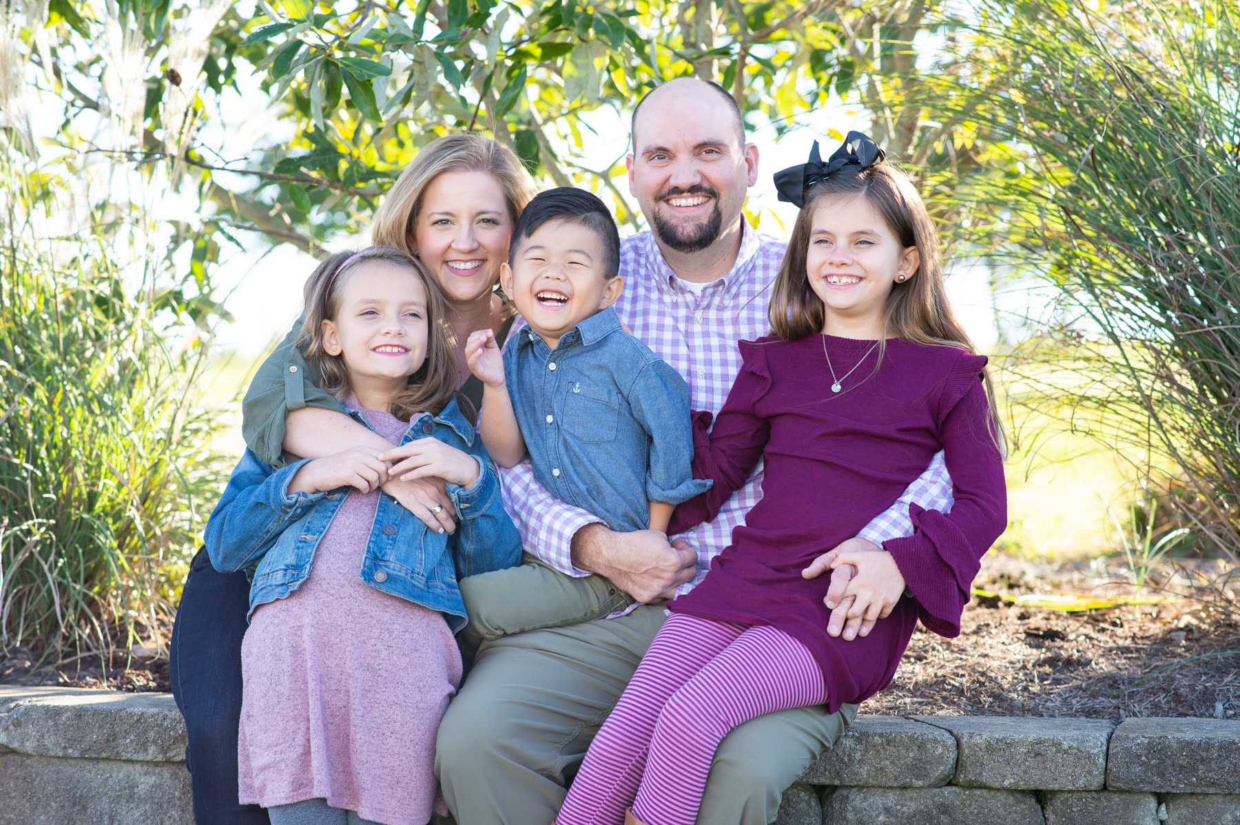 The Ranson family, owners of Dry Stack Coffee, sitting together on a stone wall in the fall
